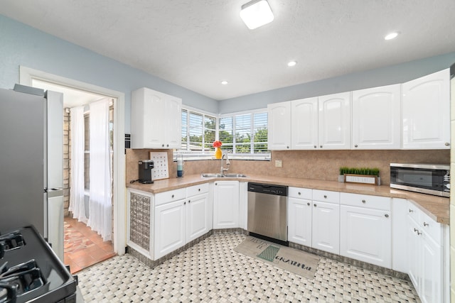 kitchen with white cabinets, appliances with stainless steel finishes, a textured ceiling, and sink