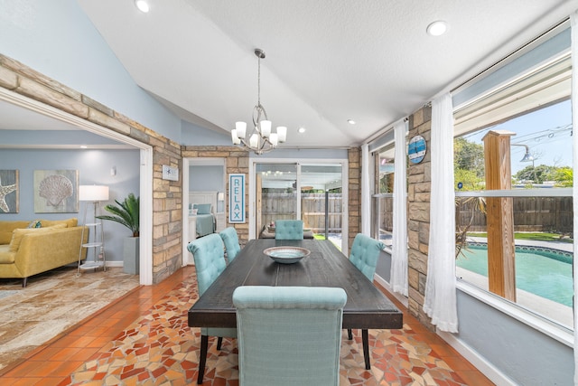 tiled dining space featuring a textured ceiling, a wealth of natural light, lofted ceiling, and an inviting chandelier