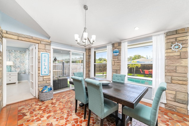 dining space with tile patterned flooring, lofted ceiling, a textured ceiling, and an inviting chandelier