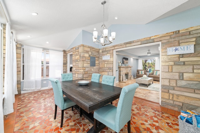 dining room featuring a chandelier, lofted ceiling, and a brick fireplace