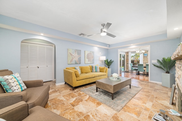 living room featuring ceiling fan with notable chandelier