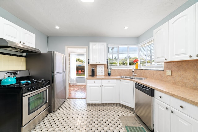 kitchen featuring white cabinetry, sink, stainless steel appliances, a textured ceiling, and decorative backsplash