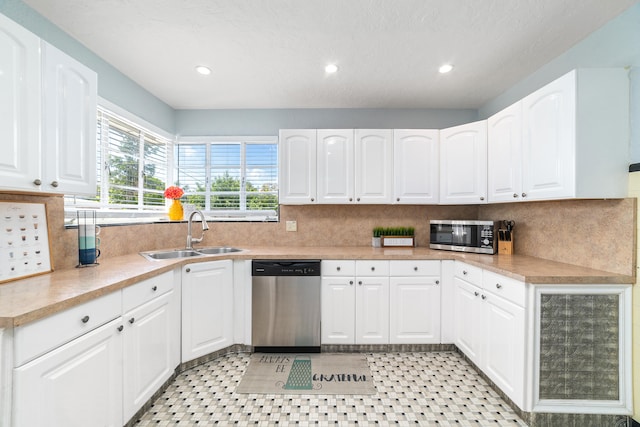 kitchen featuring appliances with stainless steel finishes, tasteful backsplash, white cabinetry, and sink