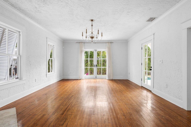 empty room with crown molding, hardwood / wood-style floors, a chandelier, and a textured ceiling