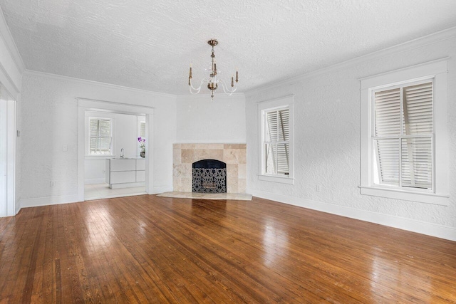 unfurnished living room with a chandelier, a textured ceiling, hardwood / wood-style flooring, and a tiled fireplace