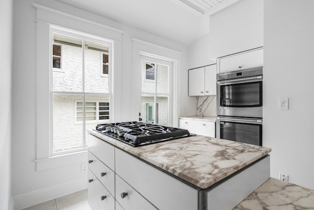 kitchen featuring gas cooktop, light stone counters, ornamental molding, double oven, and white cabinets