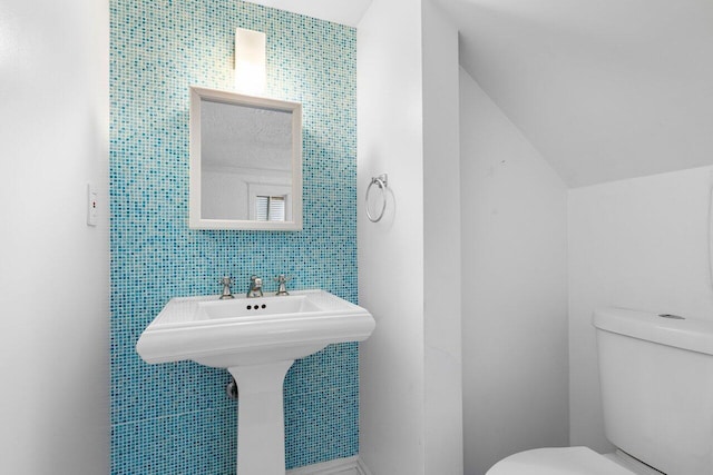 bathroom featuring sink, tile walls, and toilet