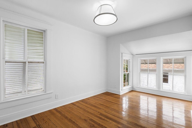 unfurnished room with hardwood / wood-style floors and vaulted ceiling