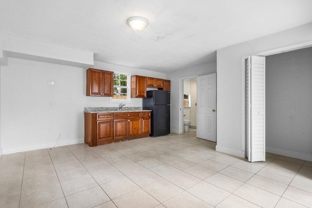 kitchen featuring black refrigerator, light tile patterned flooring, and sink