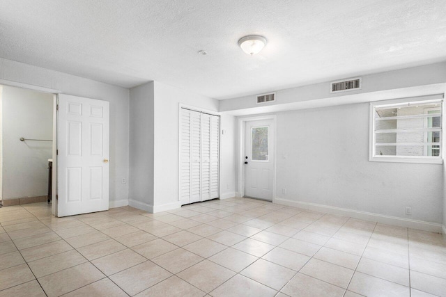 tiled empty room with a textured ceiling