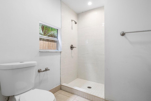 bathroom with toilet, a tile shower, and tile patterned floors