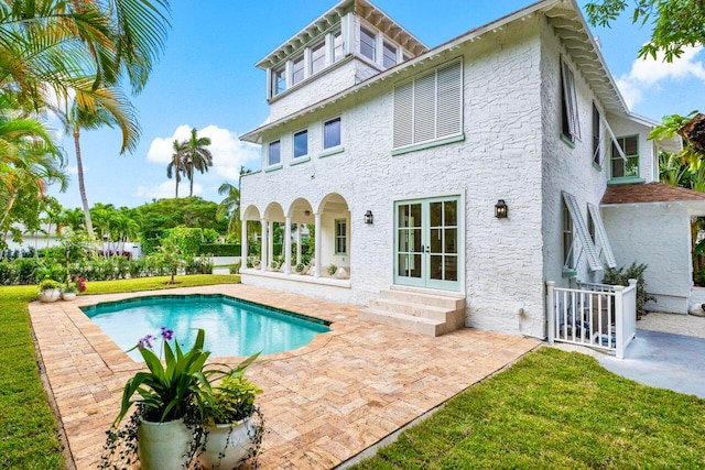 rear view of property with french doors, a patio, and a lawn