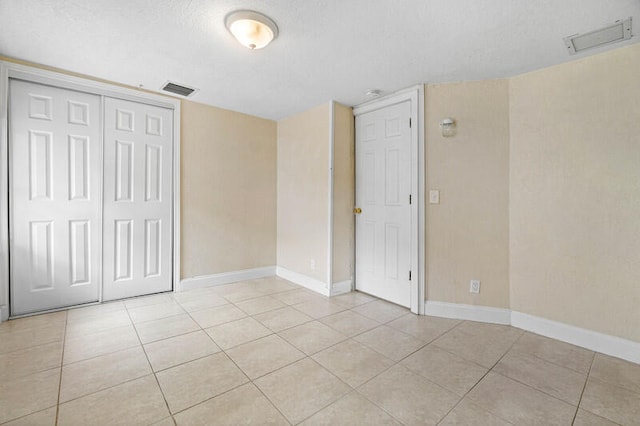 unfurnished bedroom featuring light tile patterned floors, a textured ceiling, and a closet