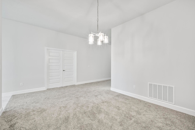 spare room featuring carpet flooring and an inviting chandelier