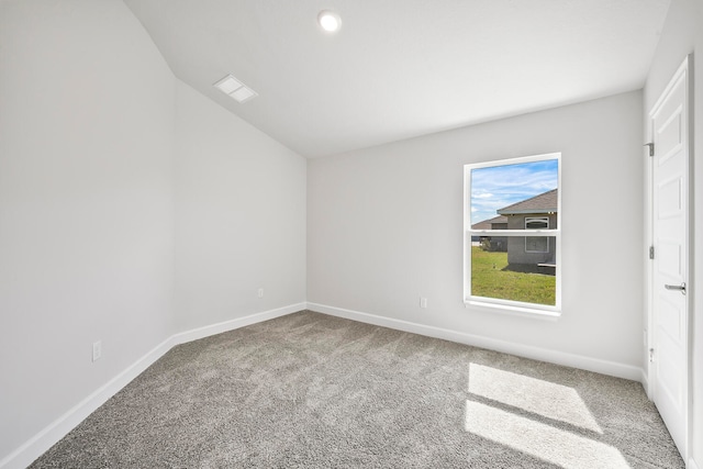 spare room featuring carpet floors and vaulted ceiling