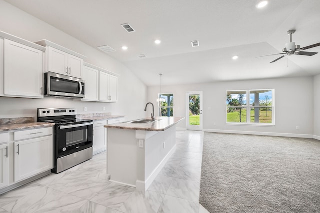 kitchen featuring appliances with stainless steel finishes, vaulted ceiling, sink, a center island with sink, and white cabinetry