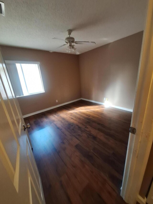 spare room featuring ceiling fan, dark wood-type flooring, and a textured ceiling