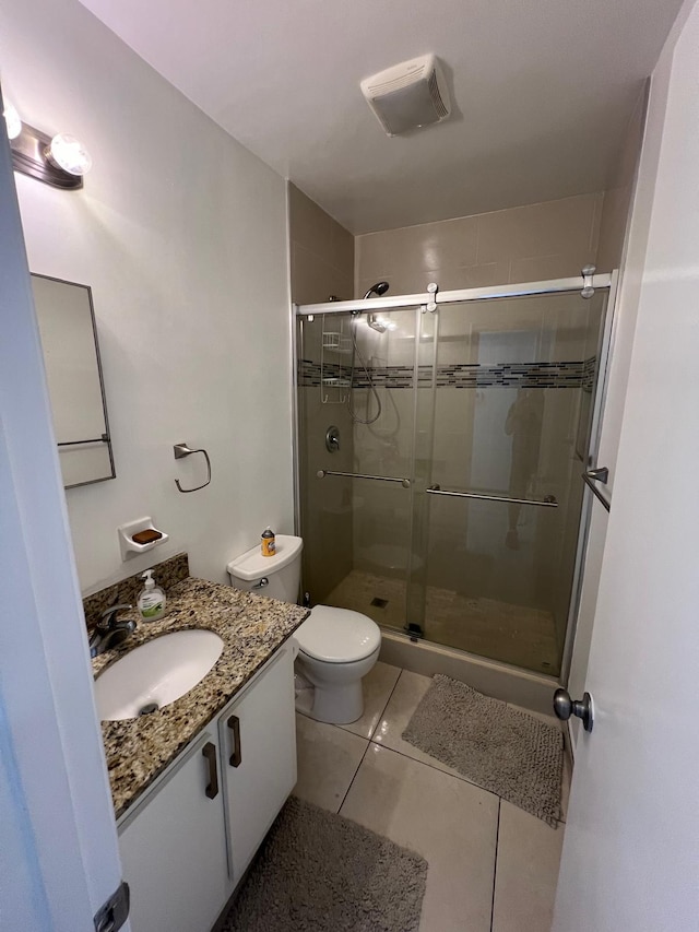 bathroom with tile patterned floors, toilet, vanity, and walk in shower