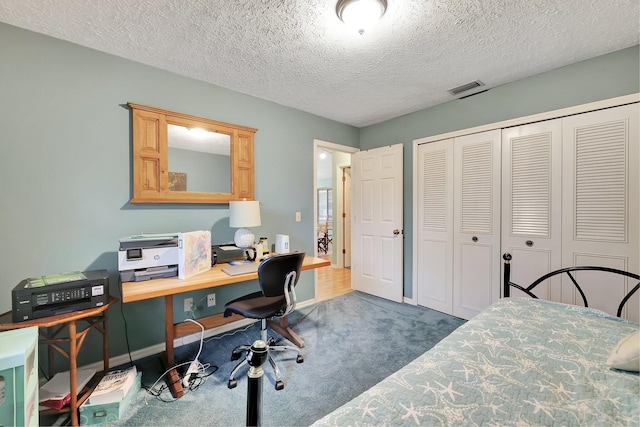 carpeted bedroom featuring a textured ceiling and a closet