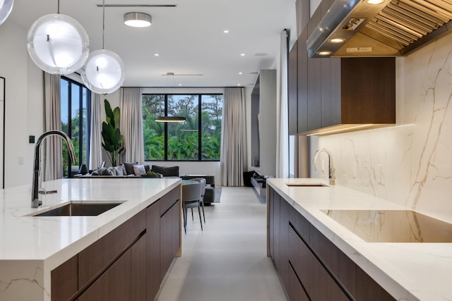 kitchen featuring tasteful backsplash, sink, wall chimney exhaust hood, and decorative light fixtures