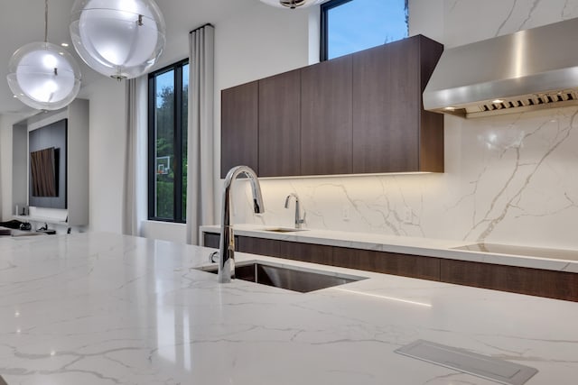 kitchen featuring pendant lighting, sink, plenty of natural light, and wall chimney range hood