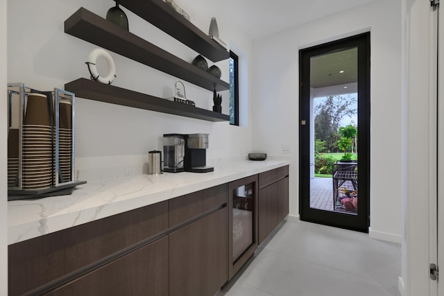 bar featuring dark brown cabinetry, light stone countertops, and wine cooler