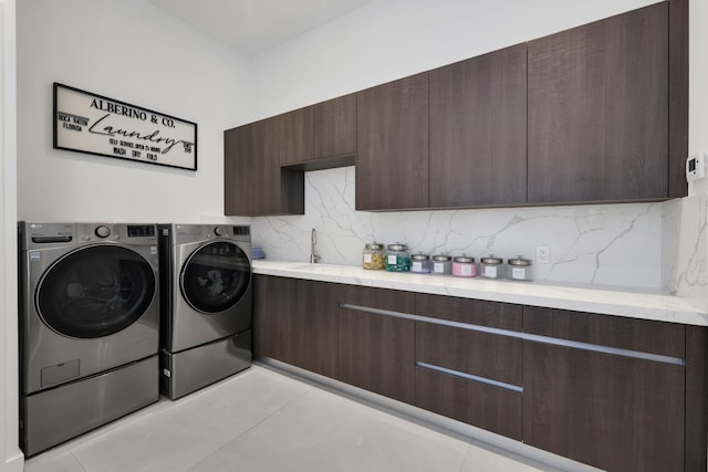 clothes washing area featuring cabinets, sink, and washing machine and clothes dryer