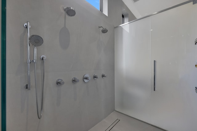 bathroom with a tile shower and tile patterned flooring