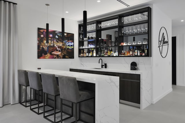 bar featuring light stone countertops, pendant lighting, and sink