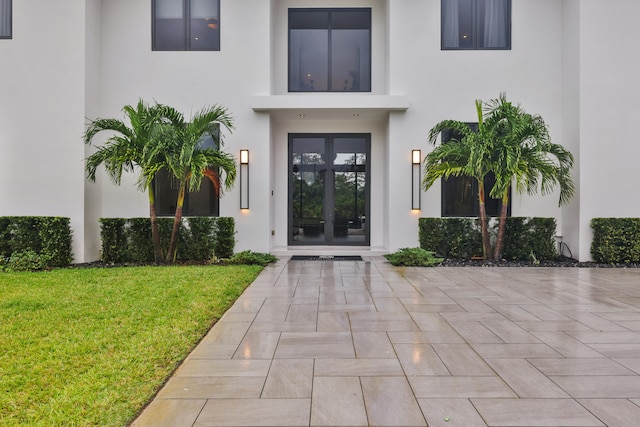 view of exterior entry with french doors and a yard