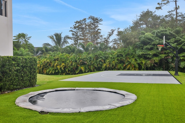 view of sport court with a lawn and a trampoline