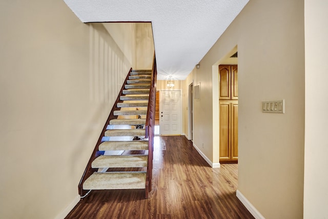 staircase with wood-type flooring and a textured ceiling