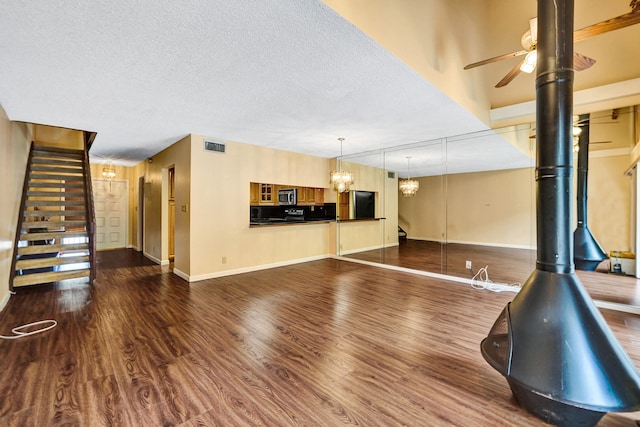 unfurnished living room featuring hardwood / wood-style floors, ceiling fan with notable chandelier, and a textured ceiling