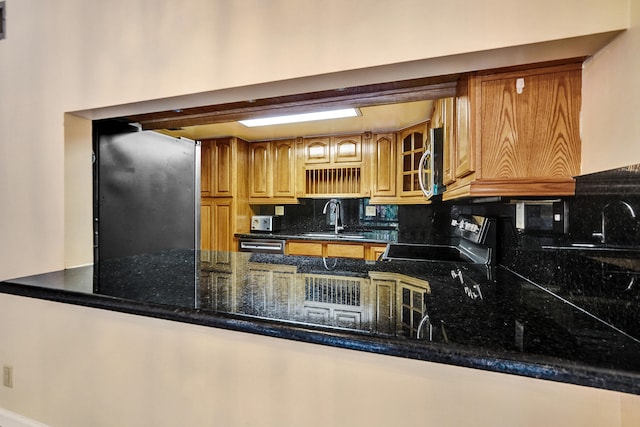 kitchen featuring decorative backsplash, dark stone countertops, sink, and stainless steel appliances