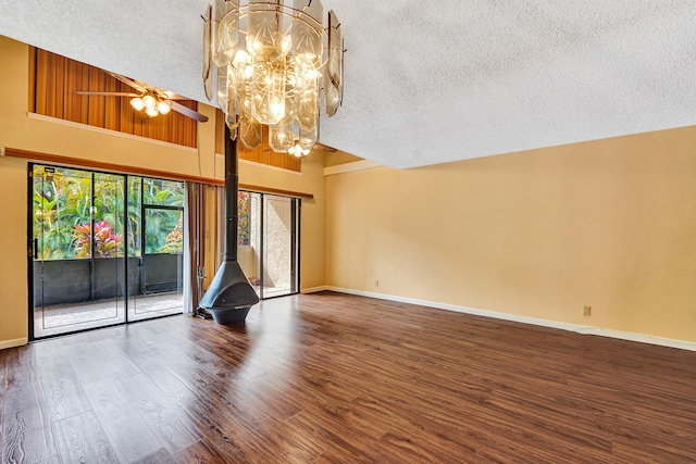 unfurnished living room with hardwood / wood-style floors, a wood stove, high vaulted ceiling, ceiling fan with notable chandelier, and a textured ceiling