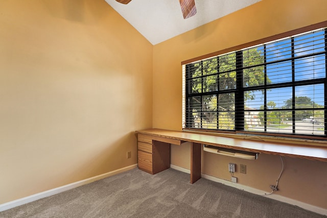 unfurnished office with ceiling fan, built in desk, light carpet, and vaulted ceiling