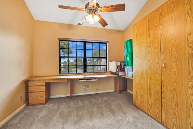 unfurnished office featuring ceiling fan, light colored carpet, built in desk, and lofted ceiling