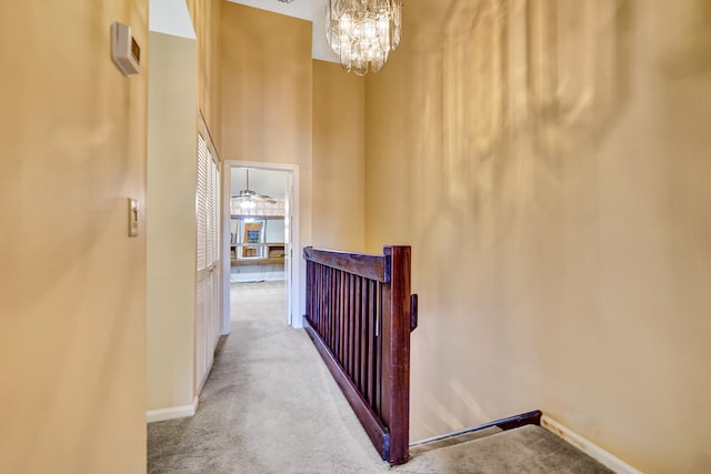 hallway with a chandelier and light colored carpet