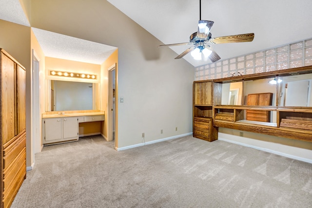 unfurnished bedroom with light carpet, vaulted ceiling, ensuite bath, ceiling fan, and built in desk