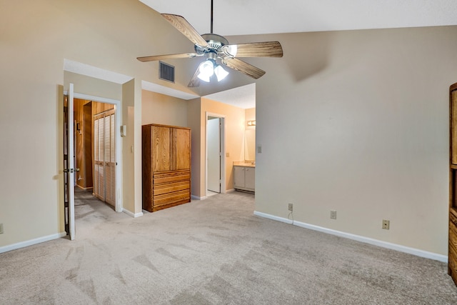 unfurnished bedroom featuring ceiling fan, light colored carpet, lofted ceiling, and ensuite bath