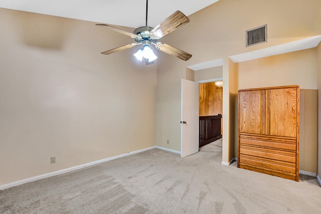 interior space with ceiling fan, a towering ceiling, and light carpet