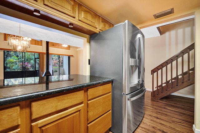 kitchen featuring pendant lighting, hardwood / wood-style flooring, dark stone countertops, stainless steel fridge with ice dispenser, and a chandelier