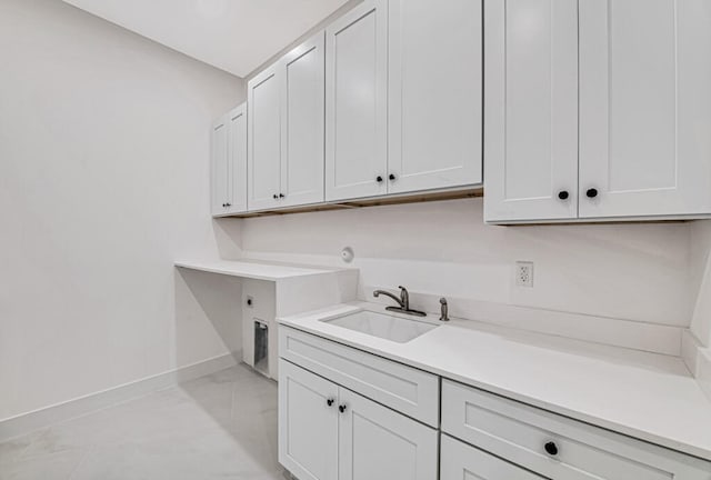 laundry area featuring cabinets, light tile patterned flooring, hookup for an electric dryer, and sink