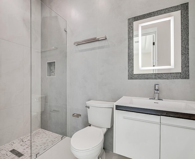 bathroom featuring a tile shower, vanity, and toilet