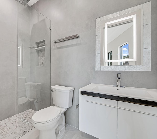 bathroom with a tile shower, vanity, and toilet