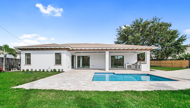 rear view of property featuring an outdoor kitchen, a fenced in pool, a yard, and a patio