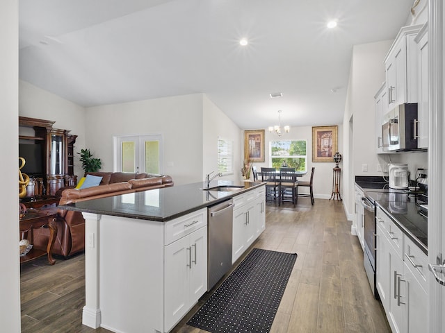 kitchen with white cabinets, dark hardwood / wood-style flooring, an island with sink, and appliances with stainless steel finishes