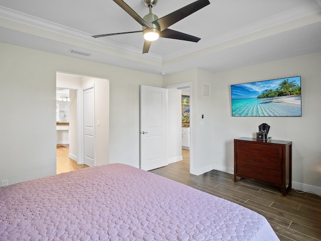 bedroom featuring ceiling fan, ornamental molding, dark wood-type flooring, and a tray ceiling