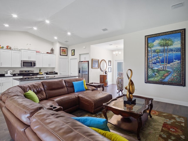 living room featuring a chandelier, dark hardwood / wood-style floors, and vaulted ceiling