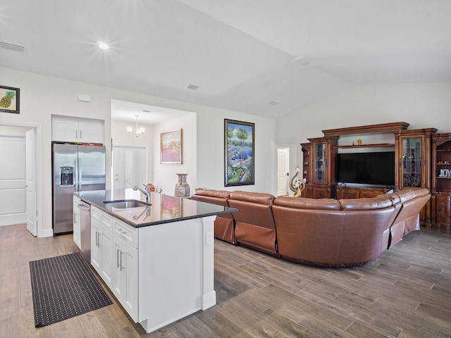 kitchen with lofted ceiling, a kitchen island with sink, white cabinets, sink, and light hardwood / wood-style flooring